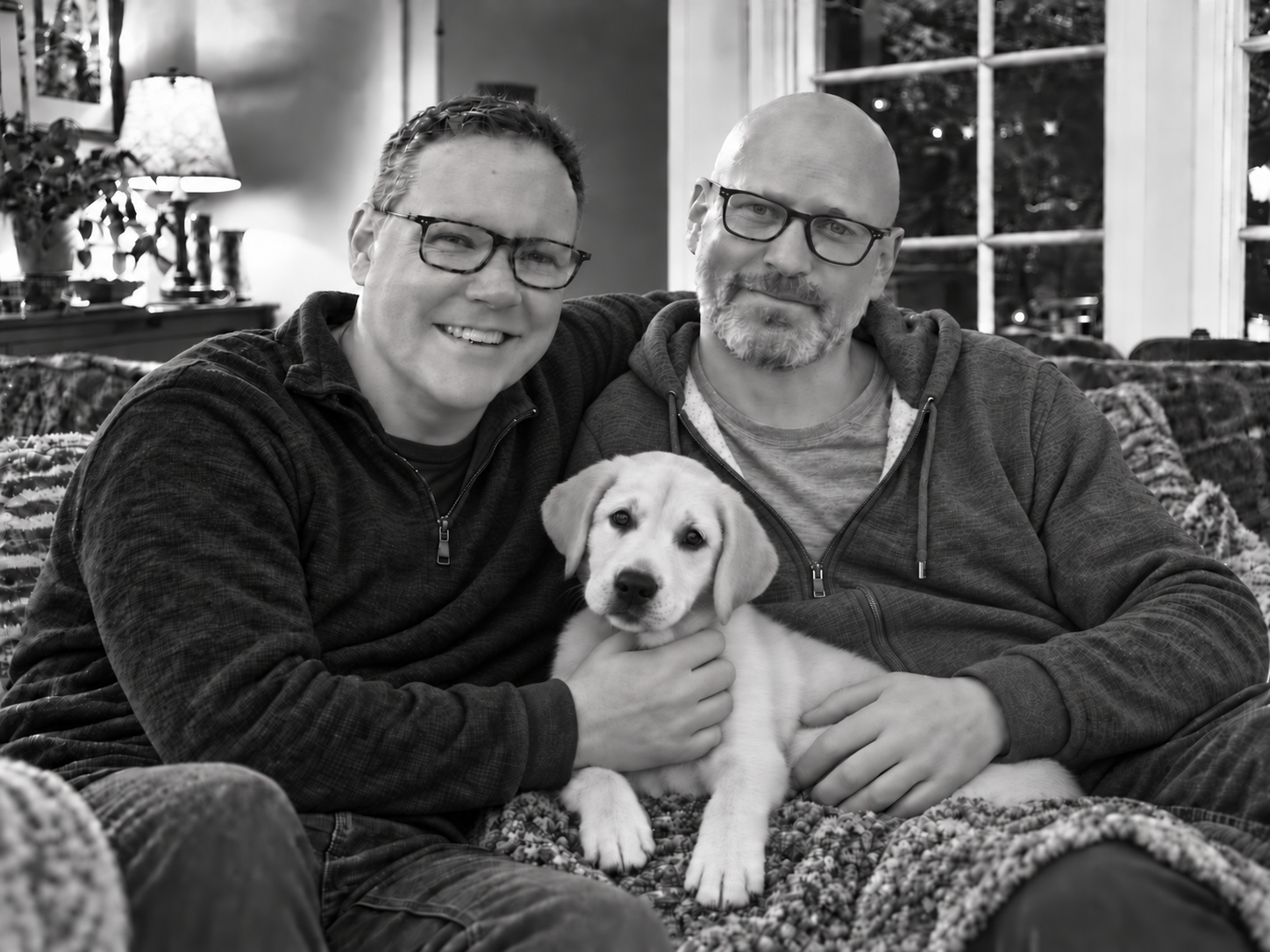 Faust and Glen sitting together at home with puppy Sidney between them