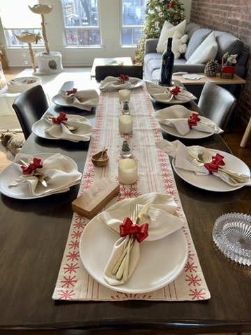 Long table set with white plates, folded napkins, and red accents