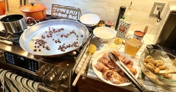 Pans and ingredients being prepared on a busy kitchen counter